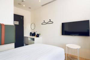淡水雀客快捷新北淡水的一间卧室配有一张床和一台平面电视