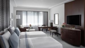 马尼拉The Peninsula Manila的酒店客房配有一张床、一张书桌和一台电视。