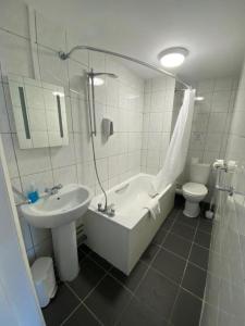 伊斯特布恩OYO Carlton Court Hotel的带浴缸、盥洗盆和卫生间的浴室