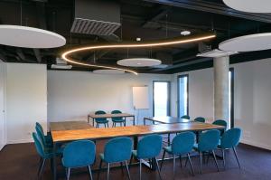 ChaurayHôtel Akena Chauray-Niort的一间会议室,配有木桌和蓝色椅子