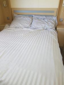 希舍姆6 berth holiday home on Ocean Edge near Morecambe的一张带条纹床单和枕头的白色床