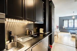 布达佩斯Bright studio apartment with a gorgeus Parliament的厨房配有黑色橱柜和水槽