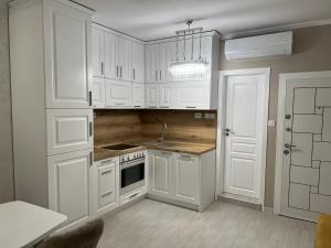 卡赞勒克DELUXE APARTAMENTS DARIS的厨房配有白色橱柜和吊灯。