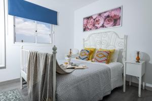 科拉雷侯Casa Virginia Corralejo by iRent Fuerteventura的卧室配有白色的床和蓝色窗帘
