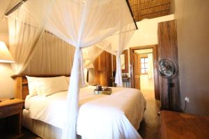 利隆圭Kumbali Country Lodge的一间卧室配有一张带天蓬的白色床
