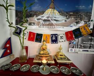 萨格勒布Himalayan Hostel的一间设有一张带祈祷旗帜和花瓶的桌子的房间