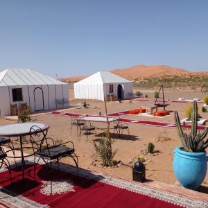 伊尔富德Merzouga dreams Camp的沙漠中一组配有桌椅的帐篷