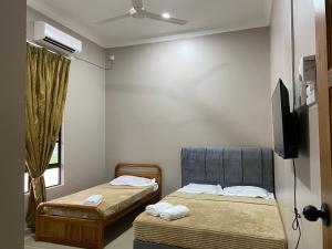 马兰Sasuka Guesthouse (Muslim Sahaja)的一间设有两张床和电视的房间
