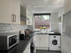 威根Modernised central Wigan townhouse sleeps up to 6的厨房配有微波炉、洗衣机和烘干机