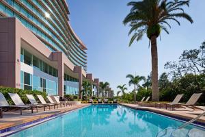 坦帕坦帕湾凯锐豪华酒店的一座带椅子的游泳池,一座建筑前的棕榈树