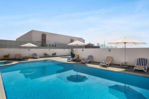 迪拜La Quinta by Wyndham Dubai Jumeirah的一座大楼内的游泳池,配有椅子和遮阳伞
