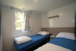 乌马格Camping Adria Mobile Home Park Umag的客房设有两张床和窗户。
