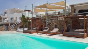 埃利亚海滩Senses Luxury Suites & Villas的一座带椅子和遮阳伞的游泳池位于一座建筑旁边