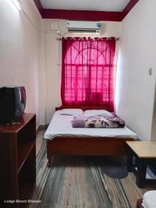 西里古里Bikash Bhawan Lodge的一间卧室设有一张床和一个红色的窗户