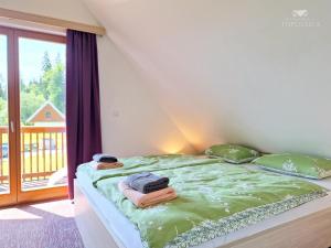 托波尔希卡Apartment HORTENZIJA near Terme Topolšica的带阳台的客房内的一张带绿色床单和枕头的床