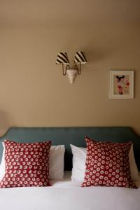 布罗德绰克The Queen's Head的一张带两个红色枕头的床和墙上的灯
