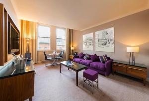 曼彻斯特曼彻斯特市政酒店的客厅配有紫色沙发和桌子