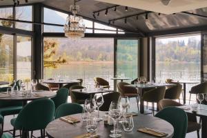 艾格布莱特勒拉克La Villa du Lac的餐厅设有桌椅和大窗户。