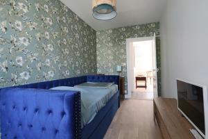 拉布尔布勒Le Gentiane - Villa Chanterive的卧室内的一张蓝色床,配有花卉壁纸