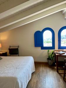 卡夫里尔斯Hostal de la Plaça - Hotel Boutique的一间卧室设有蓝色窗户和一张床