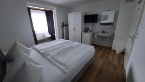 科赫姆施耐德旅馆的白色卧室设有床铺和水槽