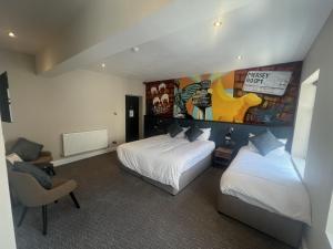 利物浦Fenwick Sunrise Hotel的酒店客房设有两张床,墙上挂有绘画作品