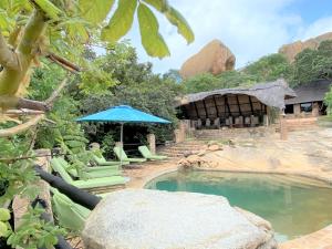 MatoposBig Cave Camp的庭院内一个带椅子和遮阳伞的游泳池