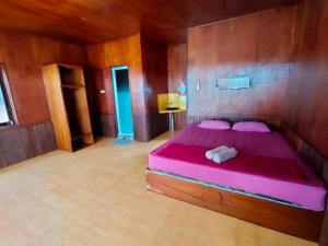 Derawan IslandsDerawan Fisheries Cottage的木制客房内的一间卧室配有粉红色的床