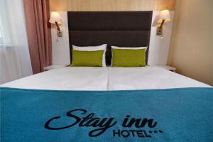 格但斯克Stay inn Hotel Gdańsk的一张床铺,上面标有酒店标志
