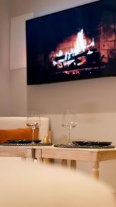 科洛布里埃Suite de Luxe Jacuzzi balnéo,King size Bed的木桌旁的两杯酒杯配有电视