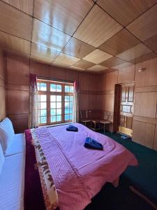 列城Zambala guest house的一间卧室配有一张带粉色毯子的大床