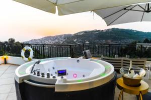 拜特丁Beit Lebbos Boutique Hotel的庭院内的热水浴池和遮阳伞