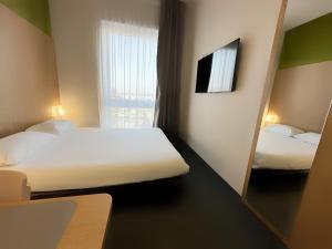 Ars-LaquenexyB&B HOTEL Metz Est Technopole Pôle Santé的小房间设有两张床和镜子