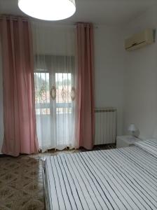 Leporano MarinaVilla Anna的一间卧室配有床和一个带粉红色窗帘的窗户。
