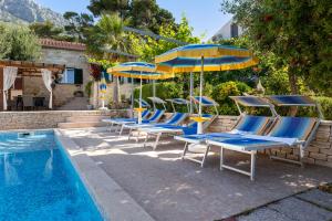 卡什泰拉Traditional stone villa to enjoy Sea, Sun, Silence, Heated Pool, and Sea View的一组椅子和遮阳伞,位于游泳池旁