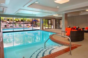 埃德蒙逊马里奥特酒店圣路易斯机场店的一个带橙色椅子的大型游泳池和一个室内游泳池
