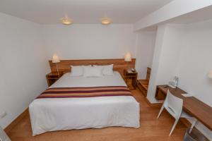 库斯科阿尔马斯库斯科广场酒店的卧室配有一张白色大床和一张书桌