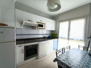 福斯Apartamento Dicar的厨房配有白色橱柜、桌子和微波炉