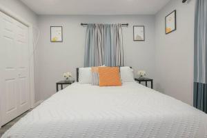 大西洋城Vibrant Island Home - 3 Bedrooms and 2 Bathrooms的卧室配有白色床和橙色枕头