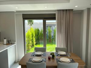 贝莱克Nirvana Belek Villas的一间带桌椅和大窗户的用餐室