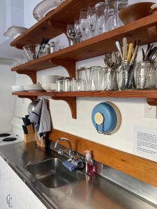 提马鲁Wee Blue BnB- Central Cosy Villa的厨房柜台设有水槽和带玻璃杯的架子