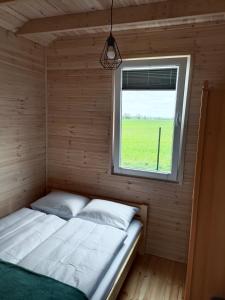 梅尔诺R&R Mielno Domki Letniskowe的窗户客房内的一张床位