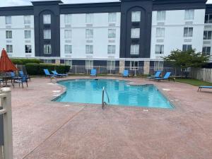 里士满里士满南部城市门户假日酒店的一个带椅子的游泳池和一个背景建筑