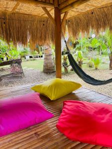 道伊斯Bohol Island Homestay的木甲板上配有两张粉红色和黄色枕头,配有吊床