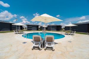 非斯Rim Aquatique Hôtel & Nature的游泳池旁的两把椅子和一把遮阳伞