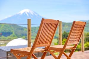 富士河口湖グランファーム富士河口湖的两把木椅坐在甲板上,上面有雪覆盖的山