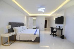ApalengJ&V Hotel and Resort的一间卧室配有一张床、一张书桌和一台电视。