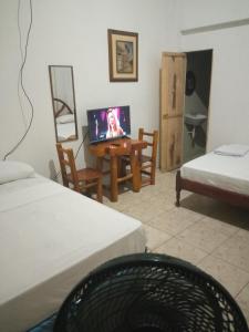 圣埃莱纳Hospederia Oasis的客房设有两张床和一张书桌及一台电视。