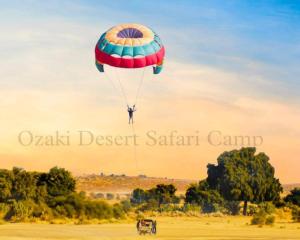 斋沙默尔Ozaki Desert Camp的飞在田野上降落伞的人