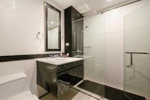 南芭堤雅Sirin Exclusive Hotel and Residence的一间带水槽和玻璃淋浴的浴室